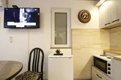 a kitchen with a table and a tv on the wall at Studio Apartman Valdez 2 in Belgrade