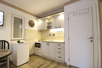 a kitchen with white cabinets and a sink and a table at Studio Apartman Valdez 2 in Belgrade