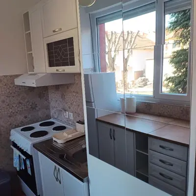 a kitchen with a stove and a window at Sarina Garsonjera in Arandjelovac