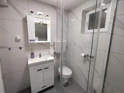 a white bathroom with a toilet and a glass shower at Nomad apartments in Belgrade