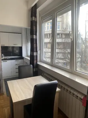 a kitchen with a table and two chairs and two windows at Skadarlija Square in Belgrade