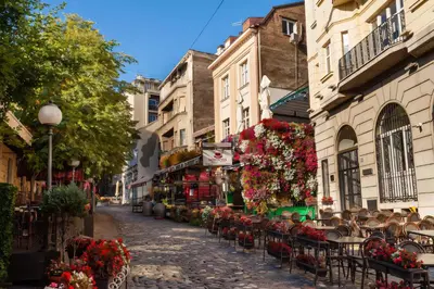 an empty street with tables and chairs and flowers at Skadarlija Square in Belgrade