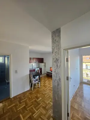 an empty living room with wooden floors and a kitchen at Apartman daba 1 in Belgrade