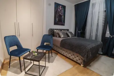 a bedroom with a bed and two blue chairs at BW Vista studio M&M - free parking in Belgrade