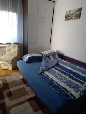 a bedroom with a blue bed with a chair and a window at Simon in Karaburma