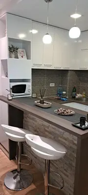 a kitchen with white cabinets and a counter with two stools at Simon in Karaburma