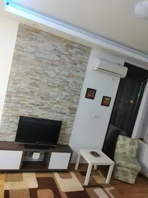 a living room with a tv and a brick wall at Simon in Karaburma