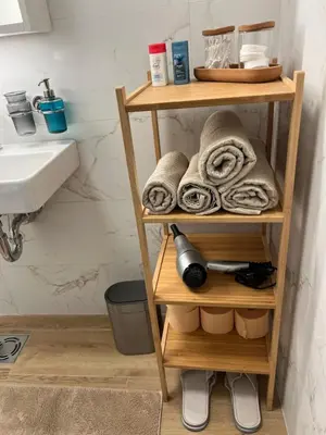 a bathroom with a shelf with towels and a sink at Ada Smart Apartment in Belgrade