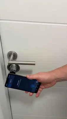 a hand unlocking a door with a remote control at Ada Smart Apartment in Belgrade