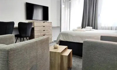 a hotel room with a bed and a tv and chairs at Open-space Apartment in the city center in Belgrade