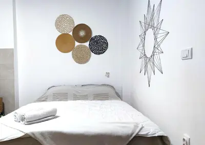 a white bedroom with a bed and decorations on the wall at Boho-Style Apartment in the city center in Belgrade