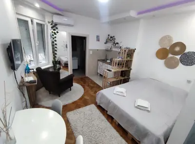 a bedroom with a bed and a living room at Boho-Style Apartment in the city center in Belgrade