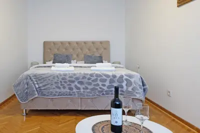 a bedroom with a bed with a bottle of wine on a table at Safari Downtown Apartment in Belgrade