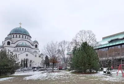 a white church with a domed building with snow on the ground at Safari Downtown Apartment in Belgrade