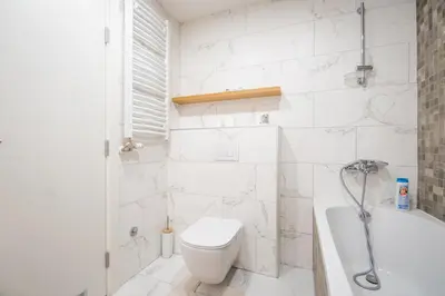 a white bathroom with a toilet and a bath tub at Monza in Belgrade