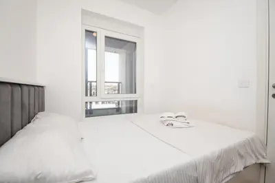a white bedroom with a bed and a window at Monza in Belgrade