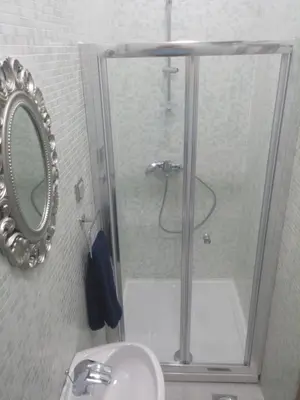 a bathroom with a shower with a sink and a mirror at Cricket 2 Hostel in Belgrade