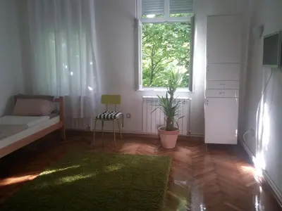 a bedroom with a bed and a window and a rug at Cricket 2 Hostel in Belgrade