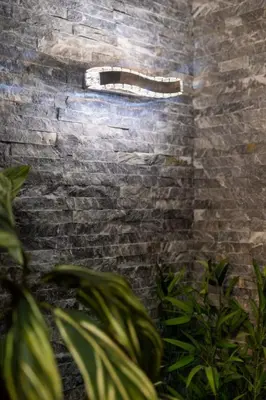 a brick wall with a window in a room with plants at Aqualux Apartment with garage in Belgrade