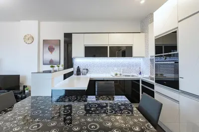 a kitchen with white cabinets and a black and white counter top at PLEASURE LUX Bg in Belgrade