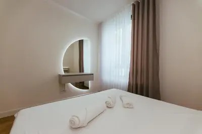 a bedroom with a white bed with a mirror and slippers at Beograd na vodi - Belgrade Waterfront Apartments in Belgrade