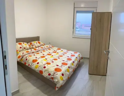 a bedroom with a bed with an orange and white comforter at Appartement 2 chambres et 1 salon près de l'aéroport de Belgrade in Belgrade
