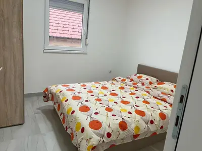 a bedroom with a bed with a comforter and a window at Appartement 2 chambres et 1 salon près de l'aéroport de Belgrade in Belgrade
