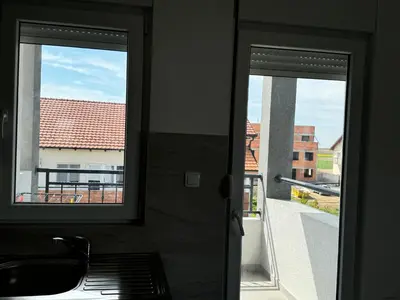 a kitchen with two windows and a sink and a balcony at Appartement 2 chambres et 1 salon près de l'aéroport de Belgrade in Belgrade