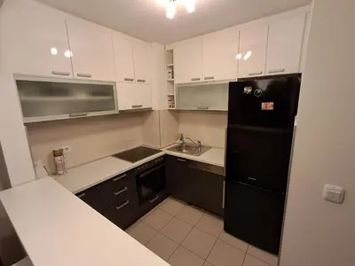a kitchen with white cabinets and a black refrigerator at Apartment Premier 4 A Blok in Belgrade