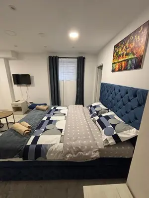 a bedroom with a large bed with a blue headboard at Apartman Knez Miloš in Belgrade