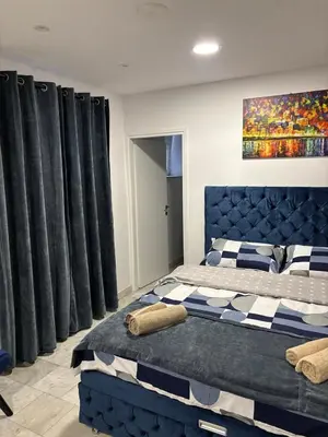 a bedroom with a blue bed and black curtains at Apartman Knez Miloš in Belgrade