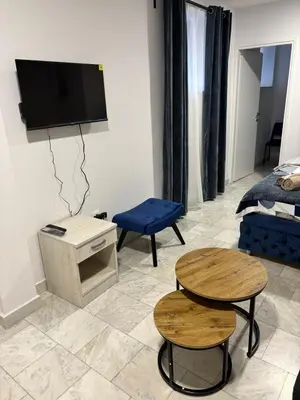 a living room with two tables and a tv on the wall at Apartman Knez Miloš in Belgrade