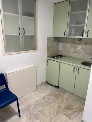 a kitchen with green and white cabinets and a blue chair at Apartman Knez Miloš in Belgrade