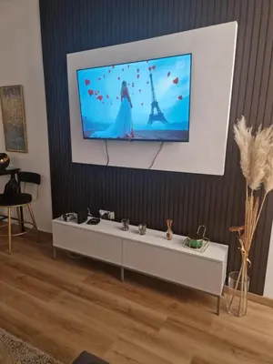 a tv screen hanging on a wall above a white table at Relax In in Belgrade