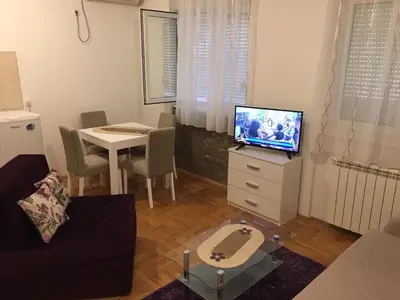 a living room with a couch and a tv and a table at Apartman Zira in Belgrade