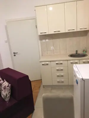 a kitchen with white cabinets and a sink and a couch at Apartman Zira in Belgrade