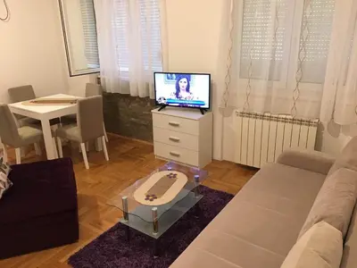 a living room with a couch and a tv and a table at Apartman Zira in Belgrade