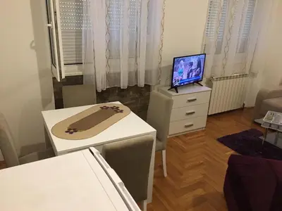 a living room with a table and a television on a dresser at Apartman Zira in Belgrade