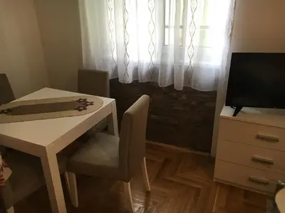 a table and chair with a table and a window at Apartman Zira in Belgrade