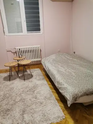 a bedroom with a bed and a table and a bed and a window at Apartman petrov 1 in Pančevo