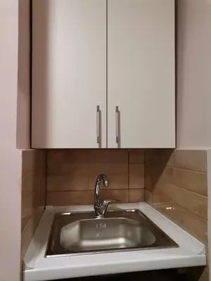 a kitchen with a sink and white cabinets at Apartman petrov 1 in Pančevo