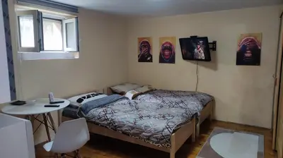 a bedroom with a bed and a table and pictures on the wall at Goxy flat in Belgrade