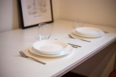 two plates and two glasses on a white table at Tiny apartment in Belgrade