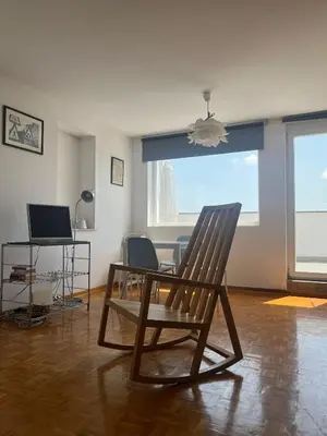a rocking chair in a living room with a table at Belgrade Panoramic View Large Terrace Free Parking in Belgrade