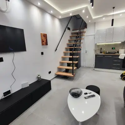 a living room with a white table and a staircase at Zeus Apartment in Rakovica