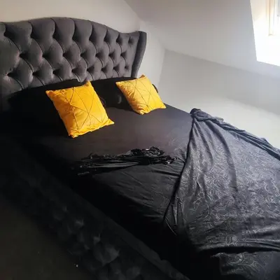 a black bed with yellow pillows and black sheets at Zeus Apartment in Rakovica