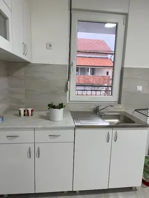 a white kitchen with a sink and a window at Airport Art Villa in Čukarica