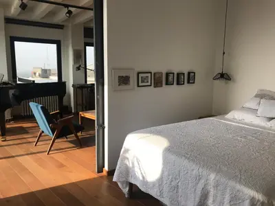 a bedroom with a bed and a chair and a piano at Exceptional City Center River View Apartment in Belgrade
