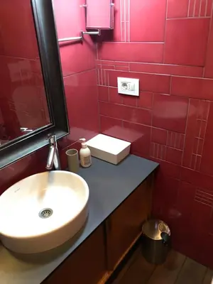 a bathroom with a sink and red tiled walls at Exceptional City Center River View Apartment in Belgrade