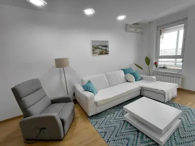 a living room with a white couch and a chair at Premium Belvil apartment, free parking in Belgrade